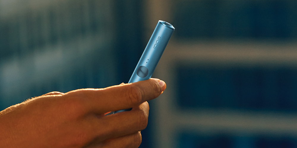 A person holding an unopened IQOS device box.